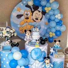 a mickey mouse themed birthday party with blue and white balloons, cake, and decorations