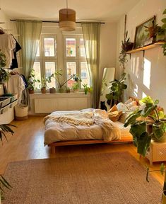 a bedroom with lots of plants in the window sill and bed on the floor