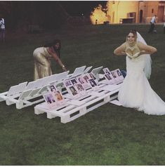 a woman in a wedding dress standing next to a white bench with pictures on it