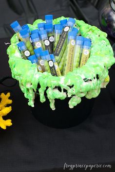 a black table topped with a green and blue bowl filled with toothpaste tubes