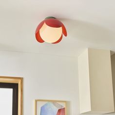 a red light hanging from the ceiling in a room with white walls and cupboards