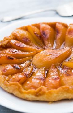 a piece of pie on a white plate with fork and knife in the back ground