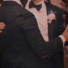 two men in tuxedos hugging each other