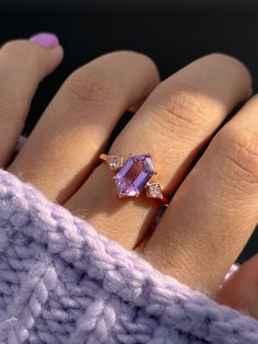 a woman's hand wearing a ring with an amethorate and diamonds