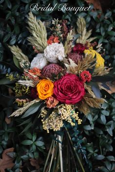 a bouquet of flowers sitting on top of a table next to some leaves and branches