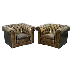 a pair of brown leather chairs sitting next to each other on top of a white background