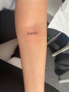 an arm with the word angel tattooed on it's left side, in black ink