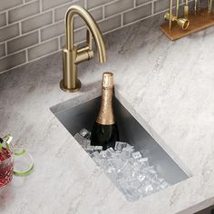 a bottle of champagne sitting in the middle of a sink filled with ice cubes