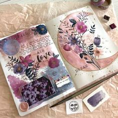 an open book with watercolors and paper on it next to some crafting supplies