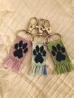 three crocheted keychains with paw prints and tassels on them