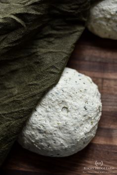 two uncooked balls of bread sitting on top of a wooden cutting board