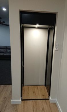 an empty room with a white wall and wooden flooring in front of the door