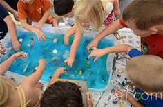 four children are playing with toys in a blue tub and text reads, create a sensory tub using something squishy