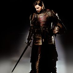 a man dressed in armor holding two large swords and standing on a black background with the caption cracked com