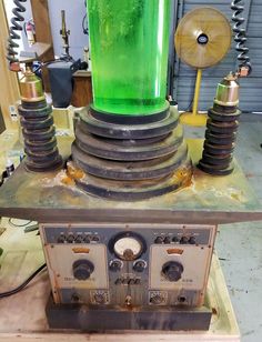 an old fashioned machine with green liquid on it's top and some wires in the background