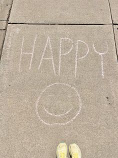 someone's feet standing in front of a sidewalk with the words happy written on it