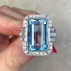 This beautiful ring features an approx 11.86-carat emerald-cut aquamarine bezel set within a handcrafted platinum mounting. The aquamarine is flanked by three baguette cut diamonds on each side and surrounded by a halo of round brilliant cut diamonds. Additional round brilliant cut diamonds are set along the shoulders. The total diamond weight is approx. 0.81 carats. This ring is decorated with fine milgrain and an openwork under-gallery. ✦ AQUAMARINE SPECIFICATIONS:    Aquamarine Cut: Emerald C Luxury Gia Certified Emerald Cut Gemstones, Luxury Gia Certified Aquamarine Ring, Luxury Aquamarine Octagon Ring, Emerald Cut Platinum Gemstones For Gifts, Luxury Octagon Aquamarine Ring, Luxury Topaz Ring Emerald Cut With Vvs Clarity, Luxury Emerald-cut Topaz Ring With Vvs Clarity, Luxury Octagon Emerald Ring With Accent Stones, Luxury Aquamarine Emerald-cut Rings