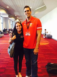 a man standing next to a woman on top of a red carpeted floor in an airport