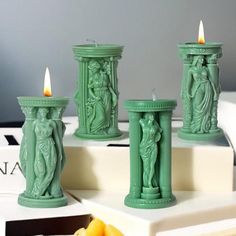 three green candles sitting on top of a table