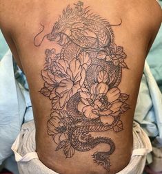 a woman with a dragon and flowers tattoo on her back