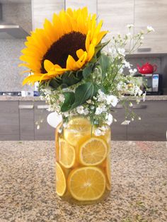 a vase filled with lemon slices and sunflowers on top of a kitchen counter