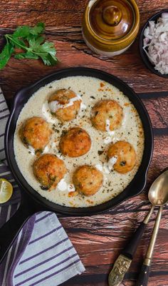 a pan filled with food on top of a wooden table next to utensils