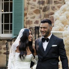 a bride and groom walking together in front of a stone building