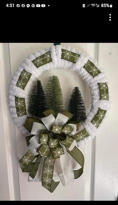 a wreath is hanging on the door with two small pine trees in front of it