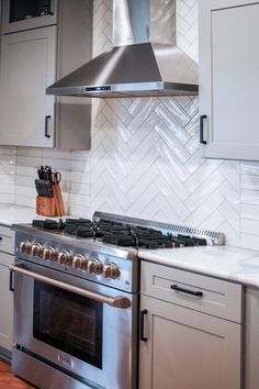 a stove top oven sitting inside of a kitchen next to white cabinets and counter tops