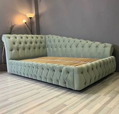 a green couch sitting on top of a hard wood floor