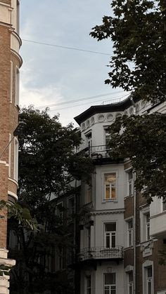 an old clock tower stands in the middle of a row of older buildings on a city street