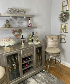 a bar with wine glasses, champagne bottles and vases on the top shelf next to two stools