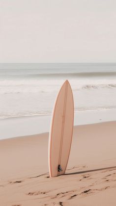 a surfboard sticking out of the sand at the beach