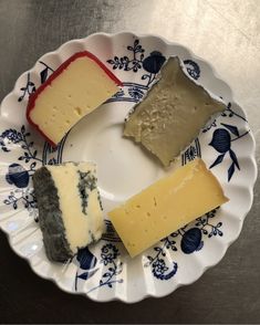 four different types of cheese on a blue and white plate