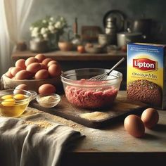 eggs, meat and flour sit on a table next to a box of lipton