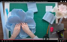 someone is working with paper flowers on a cutting board