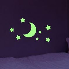 a bed room with a neatly made bed and a night sky wall decal