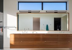 a bathroom with two sinks and a large mirror on the wall above it is also a walk in shower