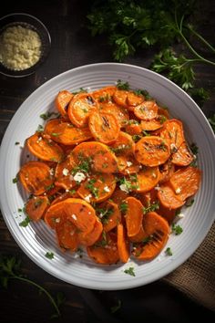 a white bowl filled with sliced up carrots and parsley on top of a wooden table