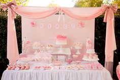 a table topped with lots of pink and white desserts