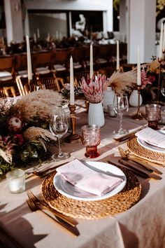 the table is set with place settings for dinner and wine glasses, napkins, candles, and flowers