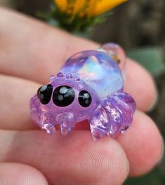 a hand holding a purple and black glass crab