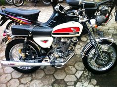 two motorcycles parked next to each other on a cobblestone street