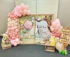 an open book surrounded by balloons and other items for a winnie the pooh birthday party