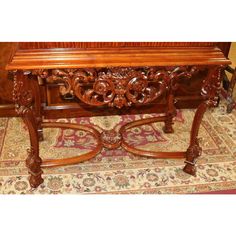 a large wooden table with carvings on the top and bottom, sitting on a rug