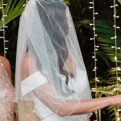 the bride and groom are looking at each other as they stand in front of string lights