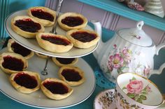 there are many pastries on the plates with jam in them and a tea pot next to it