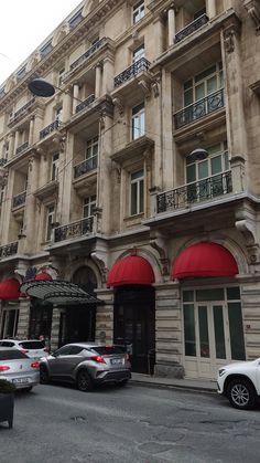 an old building with red awnings and cars parked in front