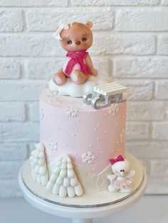 a pink and white cake with a teddy bear sitting on it's top tier