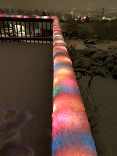 there is a light painted on the side of a long bench in the snow at night